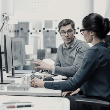 Man and woman talking at office desk. 