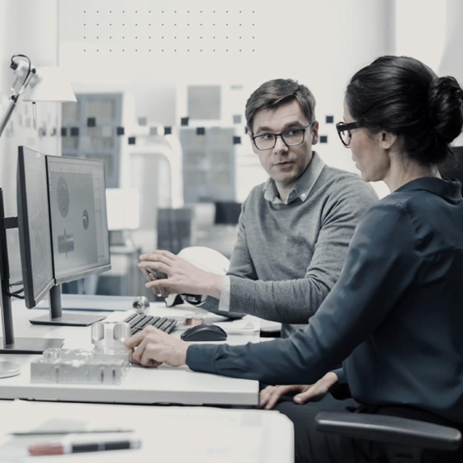 Man and woman talking at office desk. 
